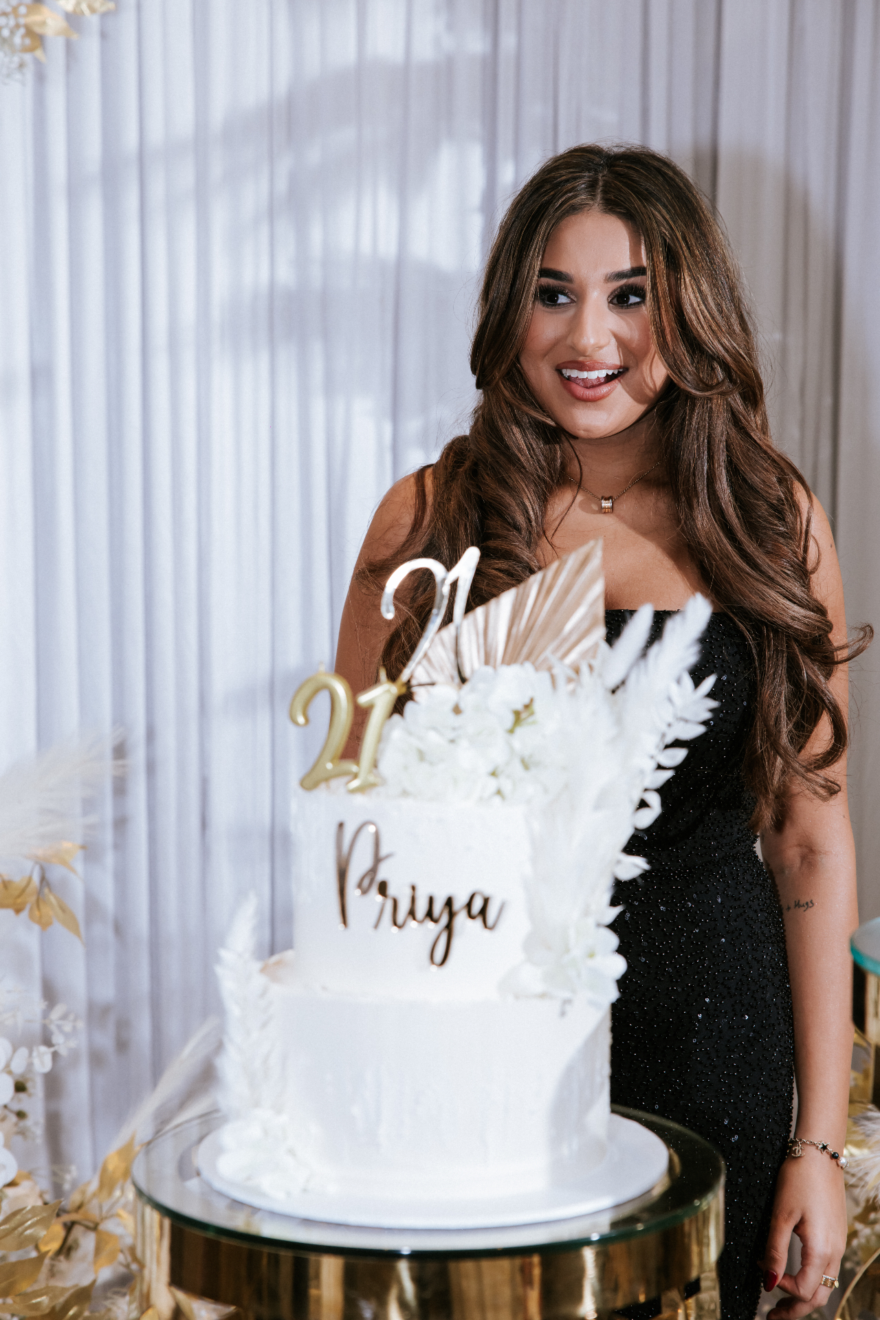 A guest smiling beside her personalised 21st birthday cake